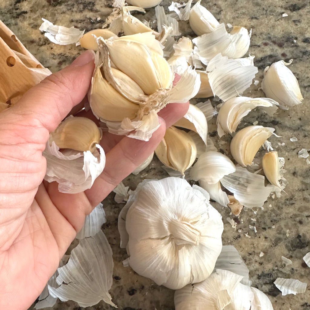 woman holding garlic cloves over kitchen countertop