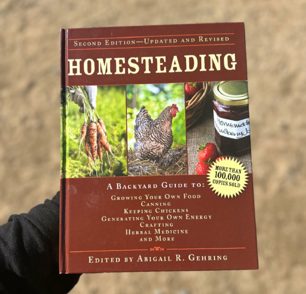 woman holding homesteading book in desert for raising tough kids