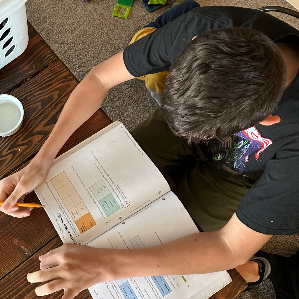 boy at table doing math, homeschool program, 4 kids